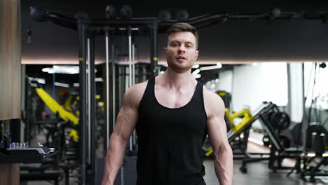 portrait of a handsome bodybuilder. young athlete with muscular body walking in modern fitness center on the background of sport simulators. sportive lifestyle.
