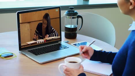 Profesora-Caucásica-Usando-Una-Computadora-Portátil-En-Una-Videollamada-Con-Una-Estudiante,-Tomando-Notas