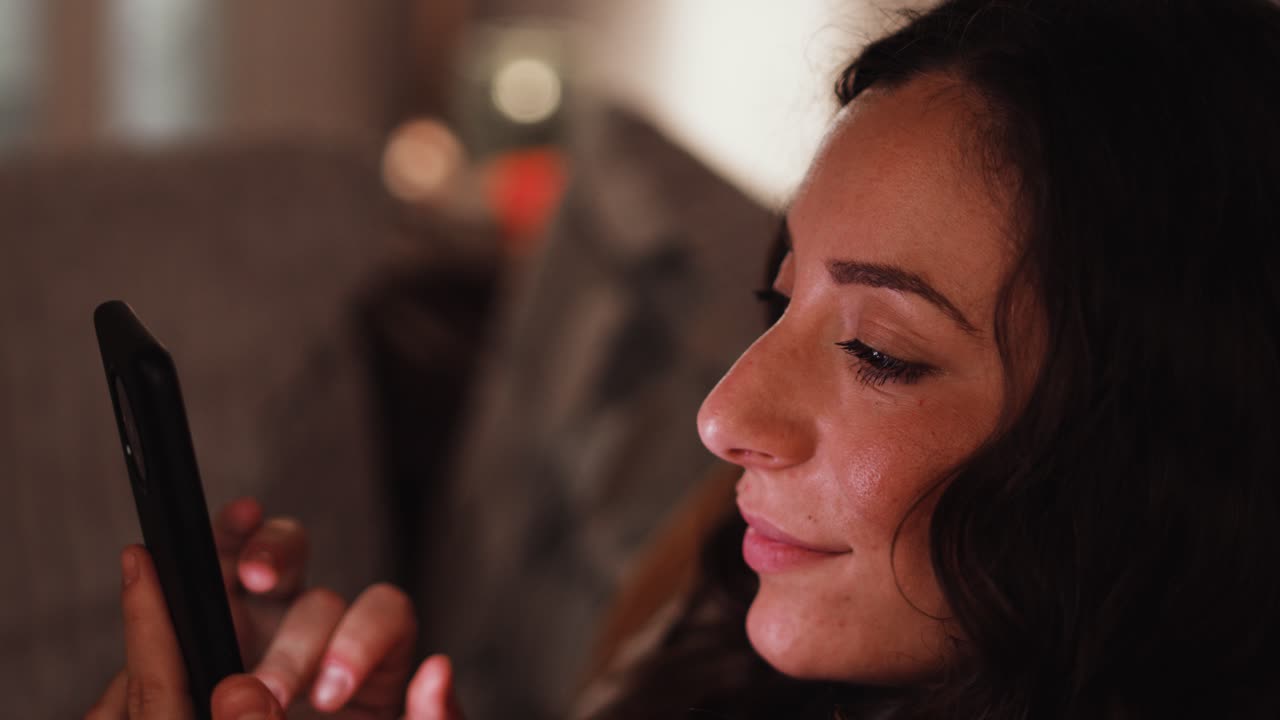 joven italiana sonriendo mientras lee y desplaza un teléfono inteligente