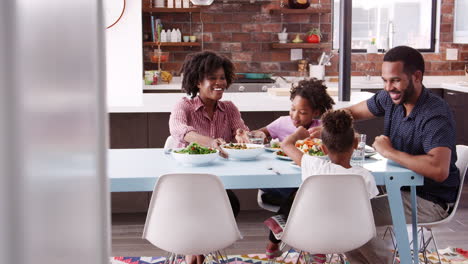 familia disfrutando de la comida alrededor de la mesa en casa juntos