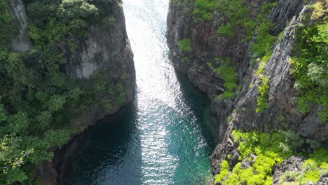 Sonnenlicht-Fällt-Durch-Hoch-Aufragende-Klippen-Und-Glitzert-Auf-Der-Wang-Long-Lagune,-Aus-Der-Luft