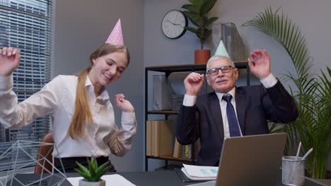 Smiling-secretary-with-handsome-senior-businessman-company-director-dancing-victory-dance-in-office