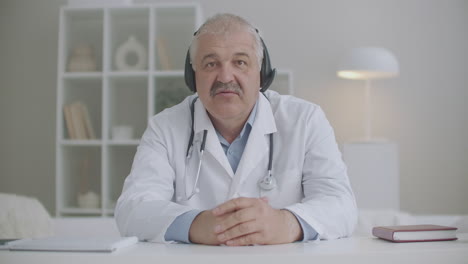 male doctor is chatting with colleagues or patients by video call sitting in clinic remote communication during pandemic of coronavirus