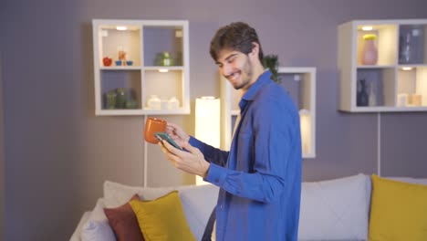 joven feliz escuchando música y bailando mientras bebe café por la mañana.