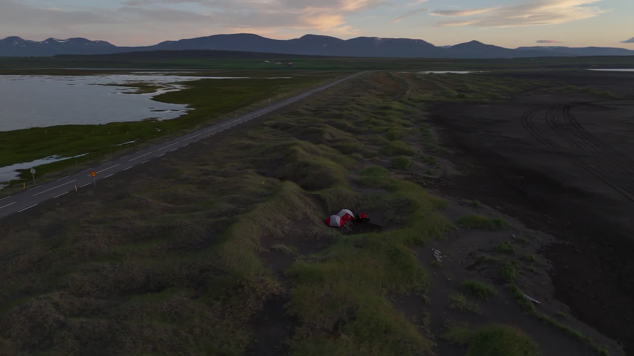 Tramonto pacifico su una spiaggia deserta di sabbia nera nel fiordo Skagafjörður vicino a Sauðárkrókur, nell'Islanda settentrionale, con acque oceaniche calme, montagne distanti e una luce dorata soffusa che si riflette sull'orizzonte