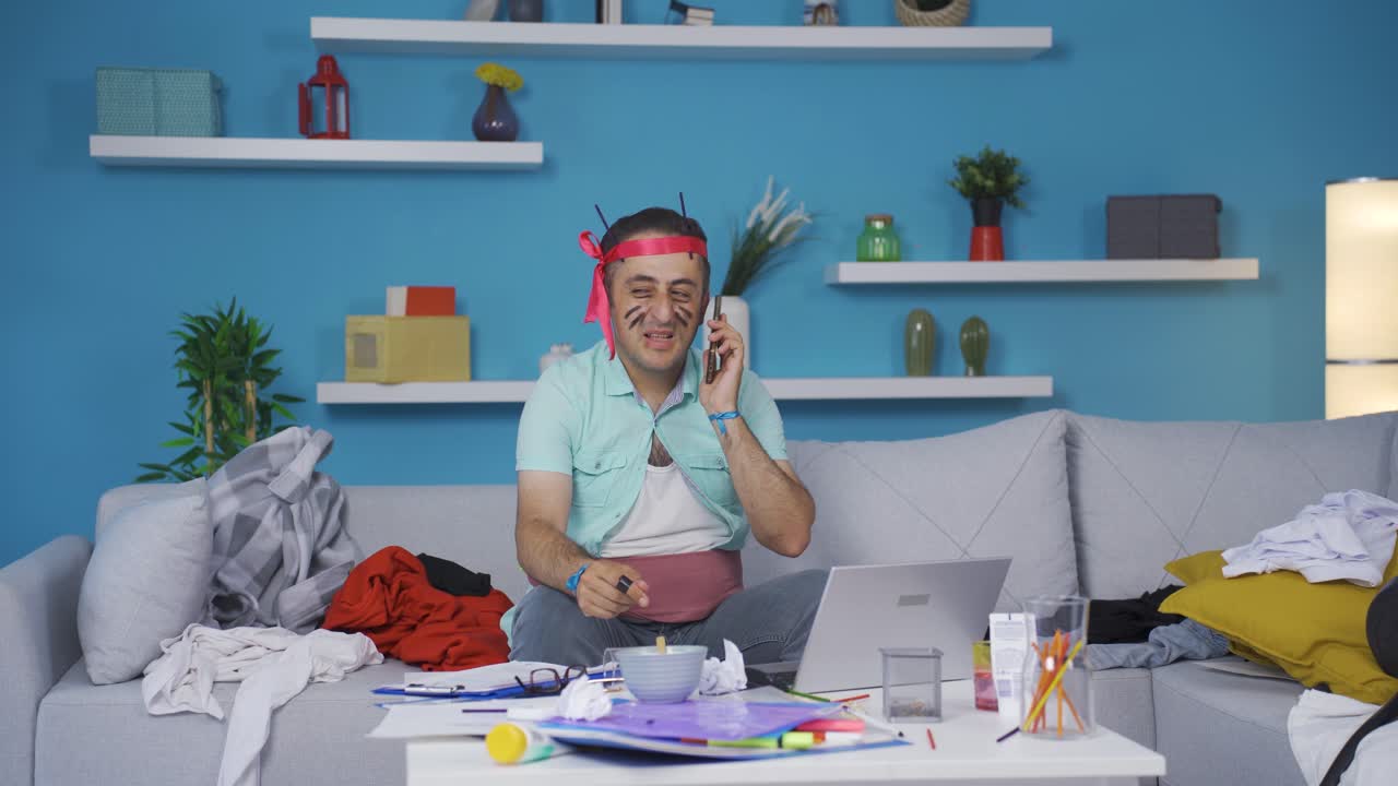 hombre gracioso que trabaja en una oficina en casa riéndose mientras habla por teléfono.