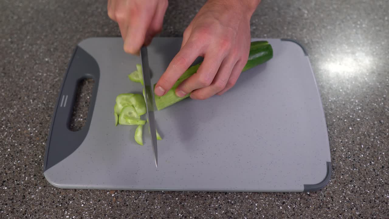 hombre cortando pepino en la tabla de cortar de la cocina