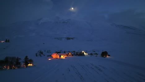 bright light above a snowy mountain in winter landscape with sporadic lighting of houses of iceland during the night