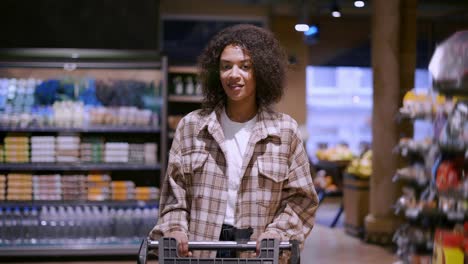 pretty african american woman walks through supermarket with cart