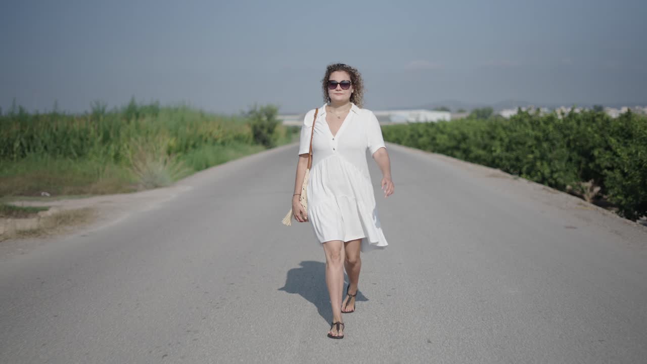 Donna che cammina su una strada di campagna in abito bianco