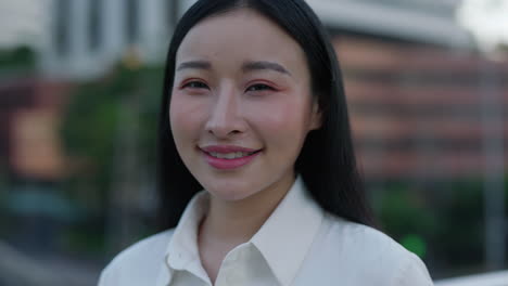 close-up portrait of a smiling young asian woman outdoors
