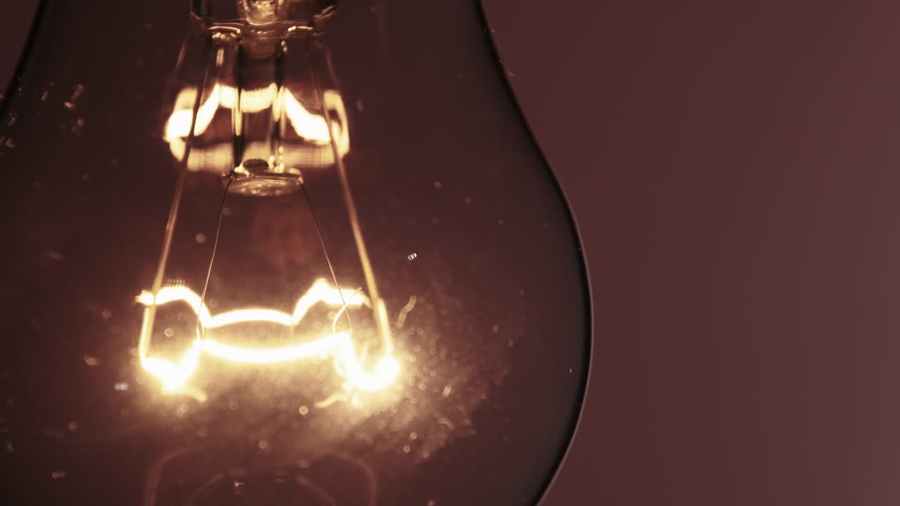 The Tungsten Filament in a Glass Lamp Close-up in Slow Motion on Red Background