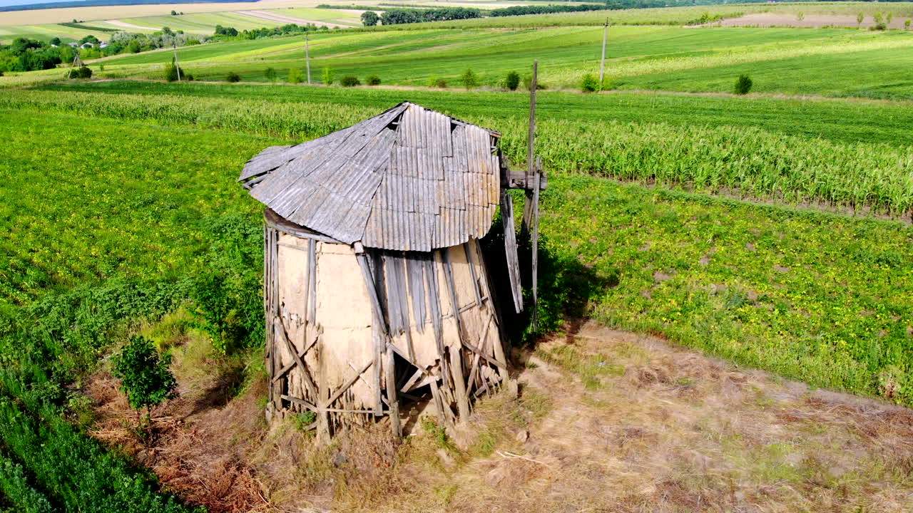 Aerial drone shot of an old abandoned and broken windmill with greenery around in Moldova. Sunny day