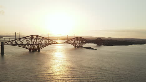 a job down style drone shot at forth rail bridge, in queensferry, scotland, uk filmed at sunset