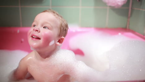 niño de dos años tomando un baño con espuma en cámara lenta