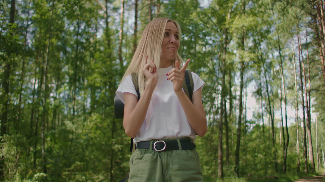 una turista divertida camina por el bosque y baila con una mochila