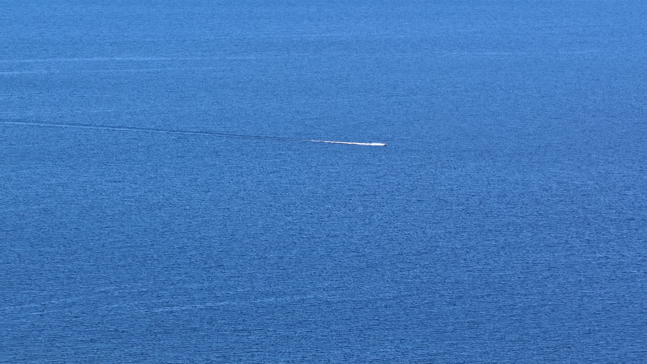 Aerial view of a speedboat cutting across the calm blue waters of the Baltic Sea near the coast of Latvia