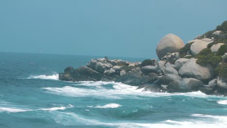 Olas-Rompiendo-Contra-Una-Pila-De-Rocas-En-Cámara-Lenta,-Disparadas-En-El-Parque-Tayrona,-Colombia