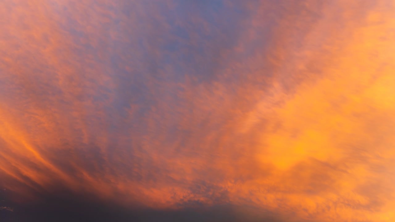 Warm orange sunset light spreading through clouds in a vivid sky scene