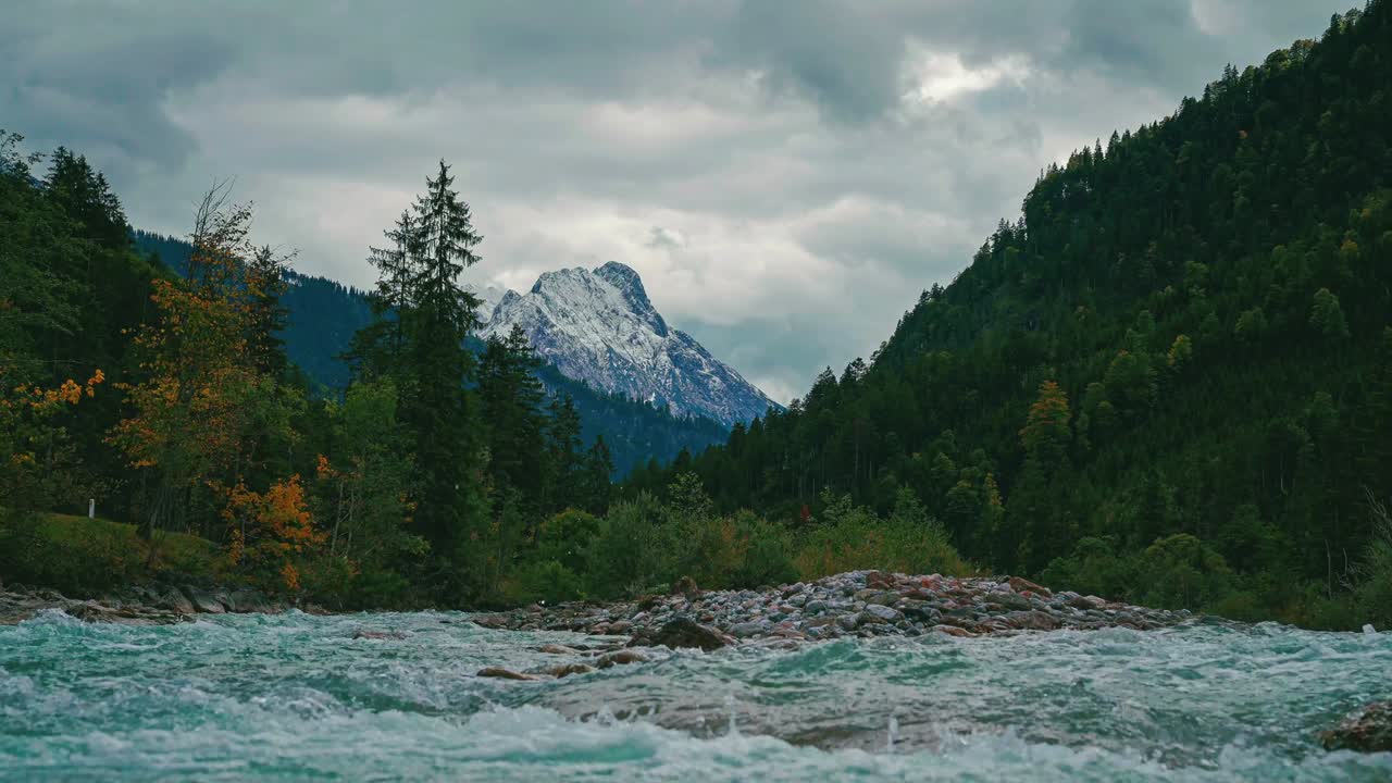 panorámico río de montaña natural cinemagraph en los alpes austriacos en el tirol con un dramático cielo nublado, cerca de la frontera alemana en otoño. el agua se apresura a lo largo de árboles de otoño coloridos. destino turístico y lugar de vacaciones.