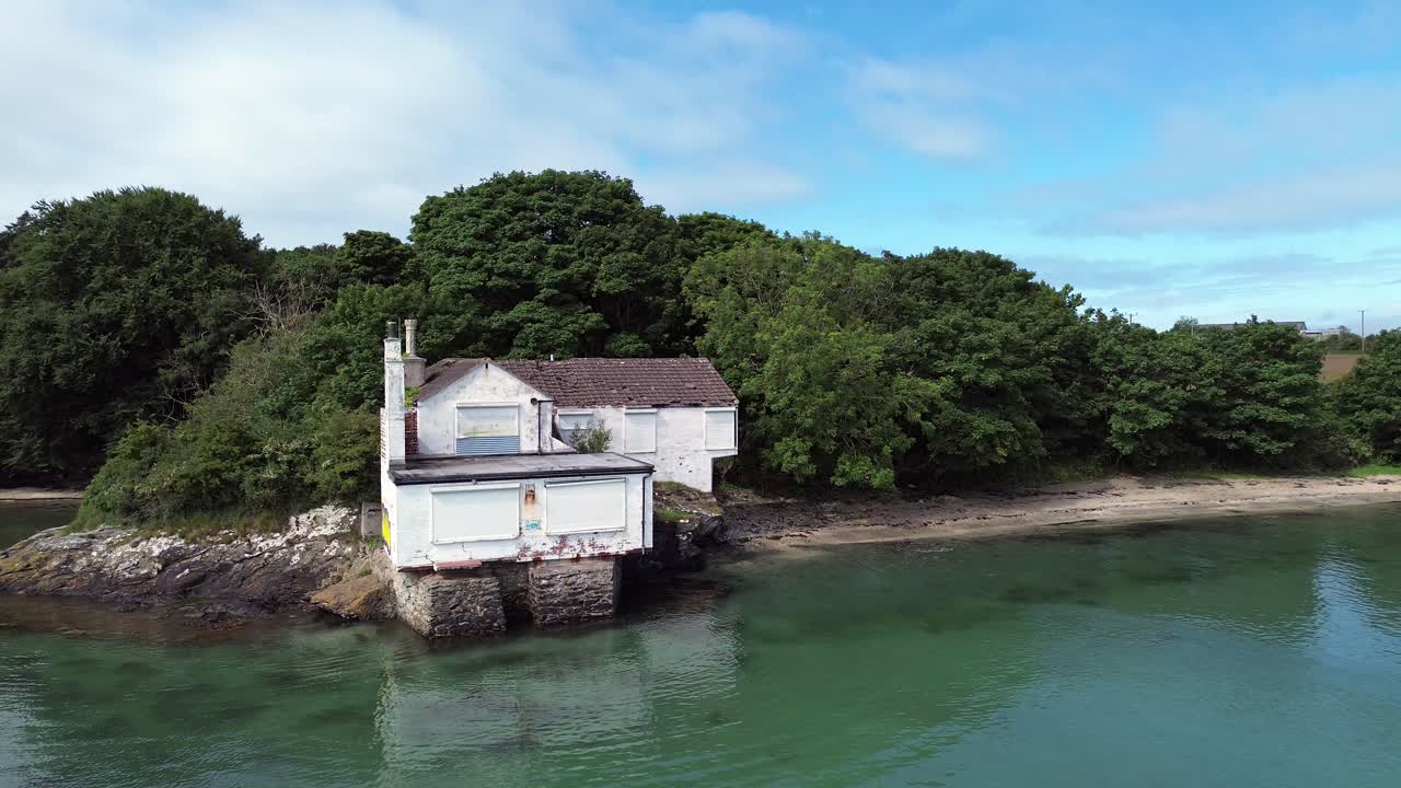 Aerial view approaching abandoned Gorsedd y Penrhyn property overlooking secluded turquoise beach