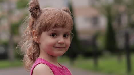 niña pequeña contra el fondo borroso de la calle de la ciudad. alegre, emociones positivas, sonrisa