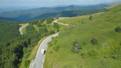 white truck going down a mountain road with panoramic view of hills