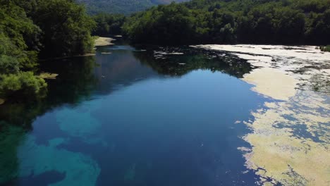 toma de dron del ojo azul en albania - dron está siguiendo el flujo del río, mostrando el reflejo del sol en el agua clara