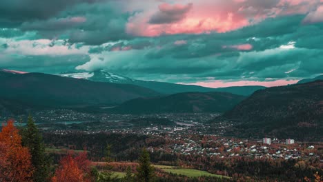 a panoramic view of a small town nestled in a mountainous valley, with dark, stormy clouds overhead