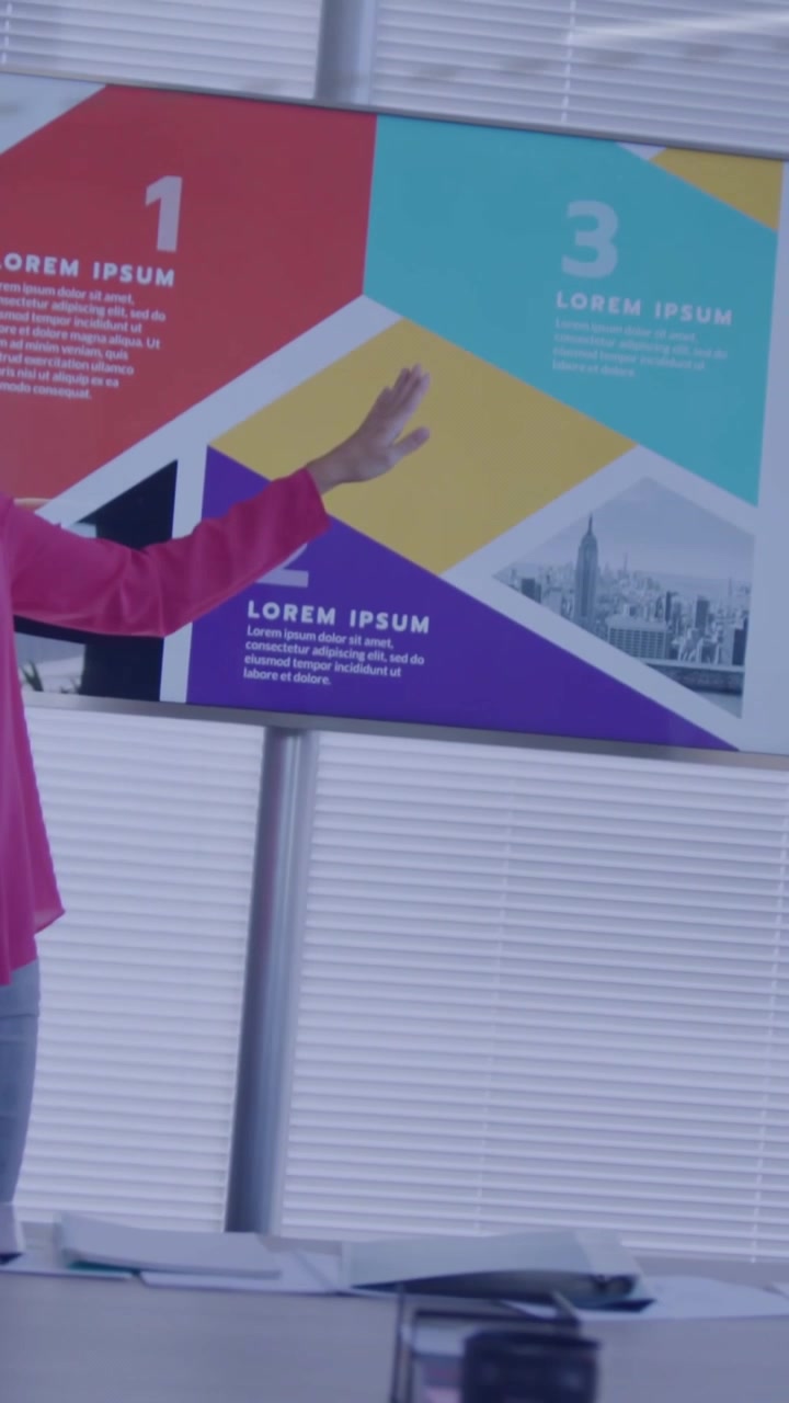 Presenting host pink-top pants starting talk explaining pointing to screen in meeting-room with AR