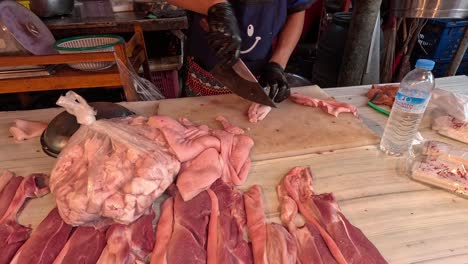 butcher cuts pork on wooden table efficiently.