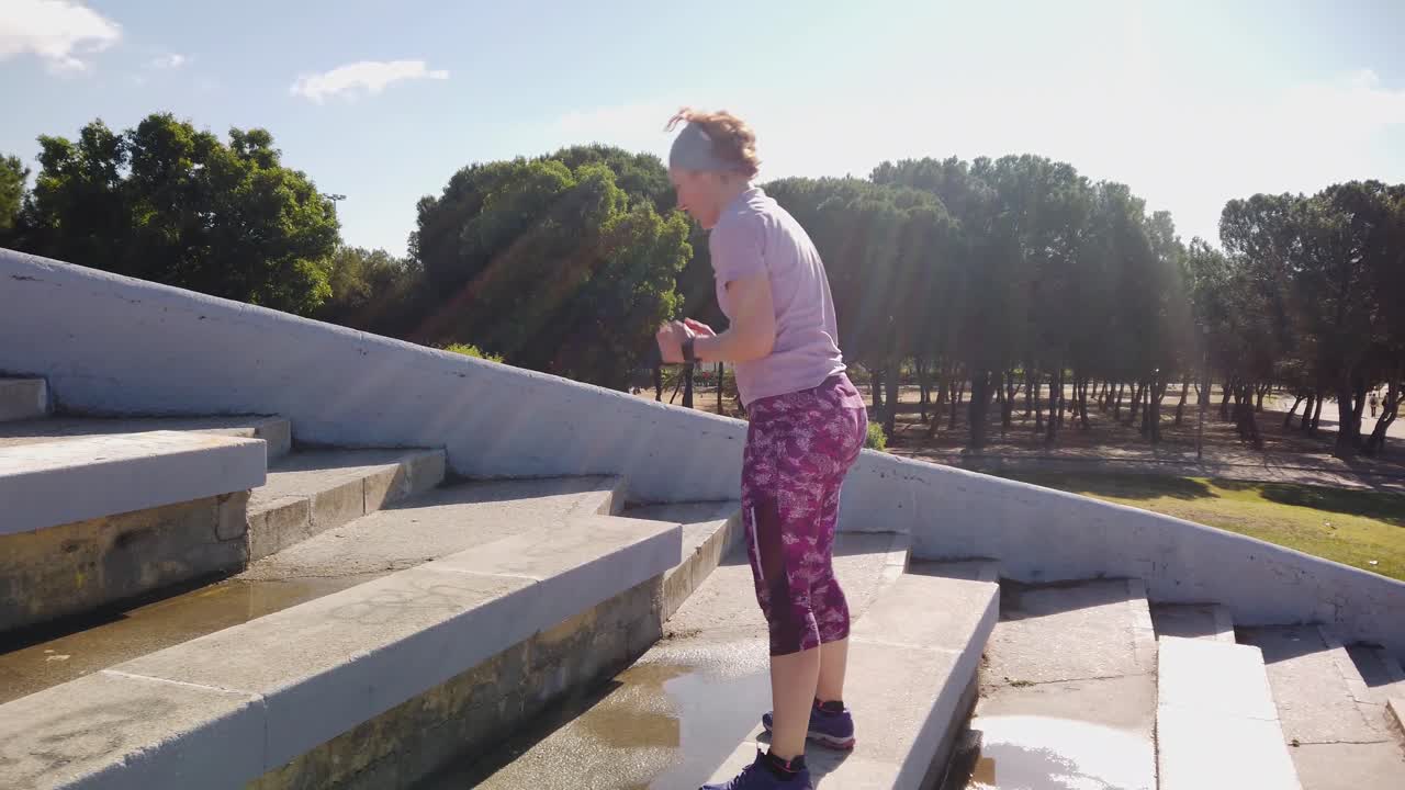 A redhead woman jumping some bleachers in a park