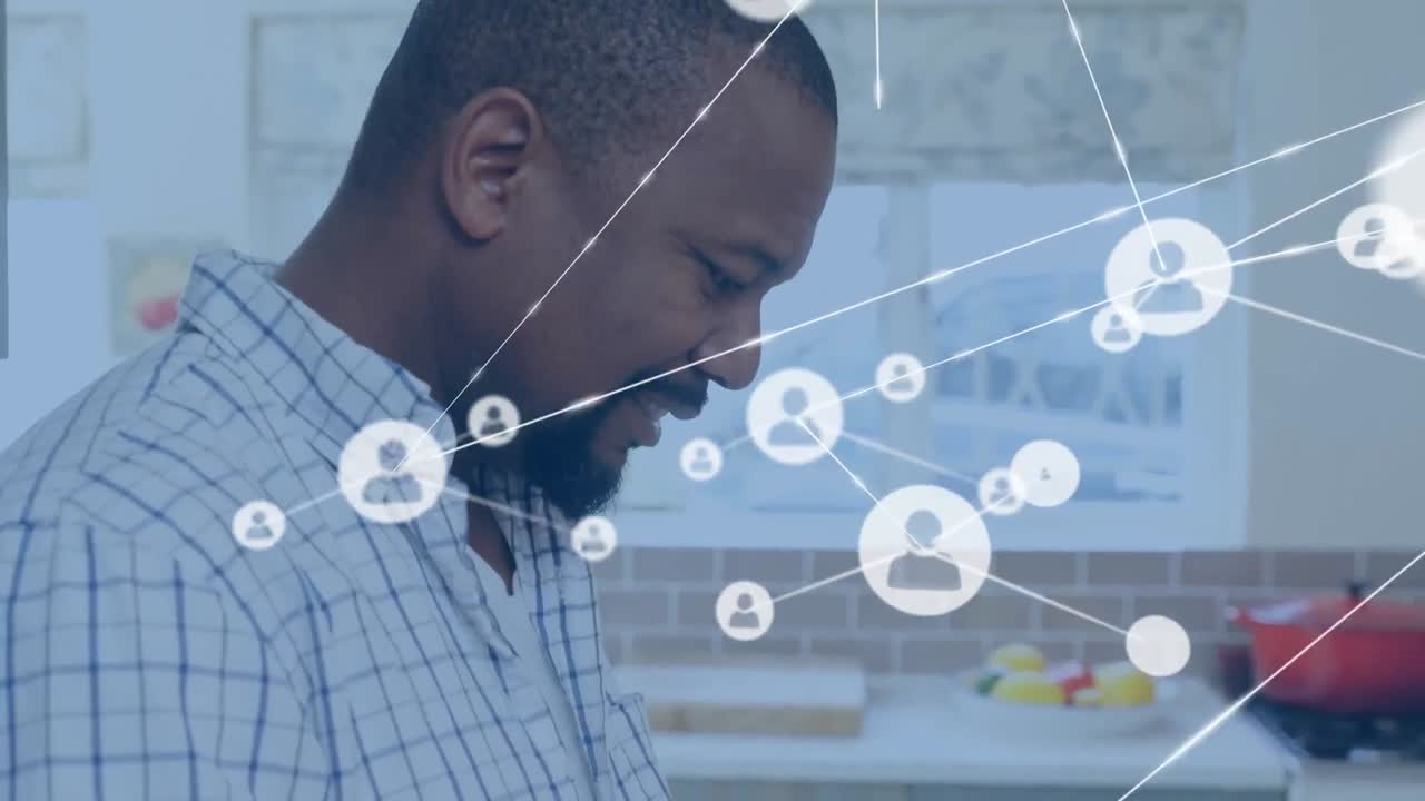 Animation of profile icons connected with lines and happy african american man using tablet at home