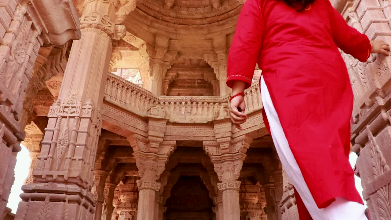 chica joven caminando en el antiguo templo tallado en piedra desde el ángulo de atrás en el día