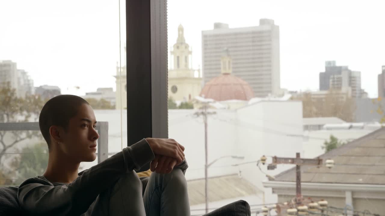 hombre sentado en el sofá cerca de la ventana en casa 4k