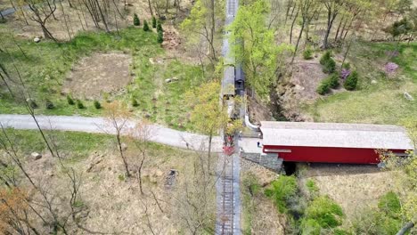 una vista aérea de un tren de pasajeros de vapor de 1860 que viaja a través de una zona boscosa en una sola vía solitaria