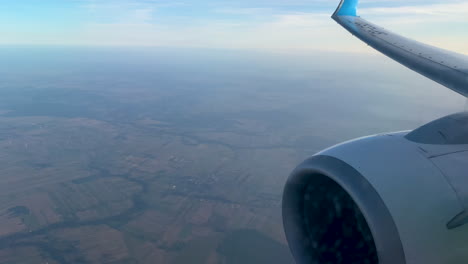 aerial view from airplane with aircrafts turbine and wing with blue tip in foreground