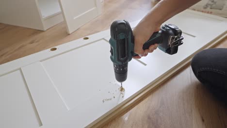 handyman use power drill for hole on white closet door, close up