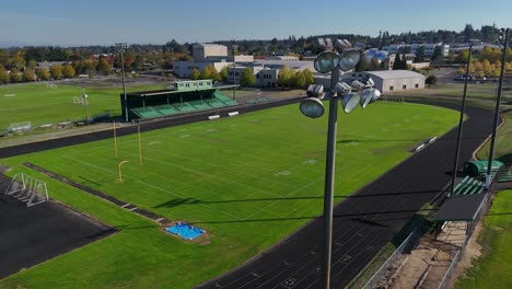 drone pass by light tower at a high school football field with a lone woman on the track