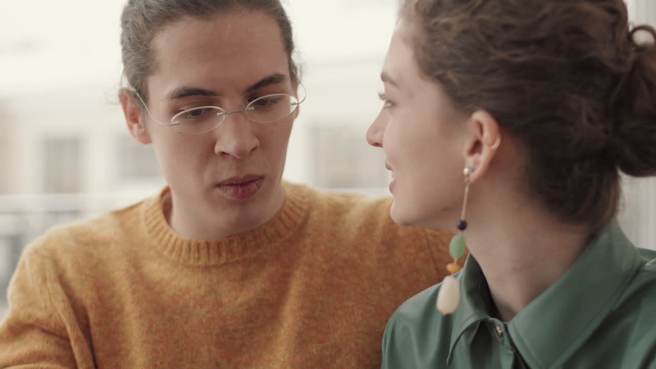 un joven y una mujer charlan en un café.