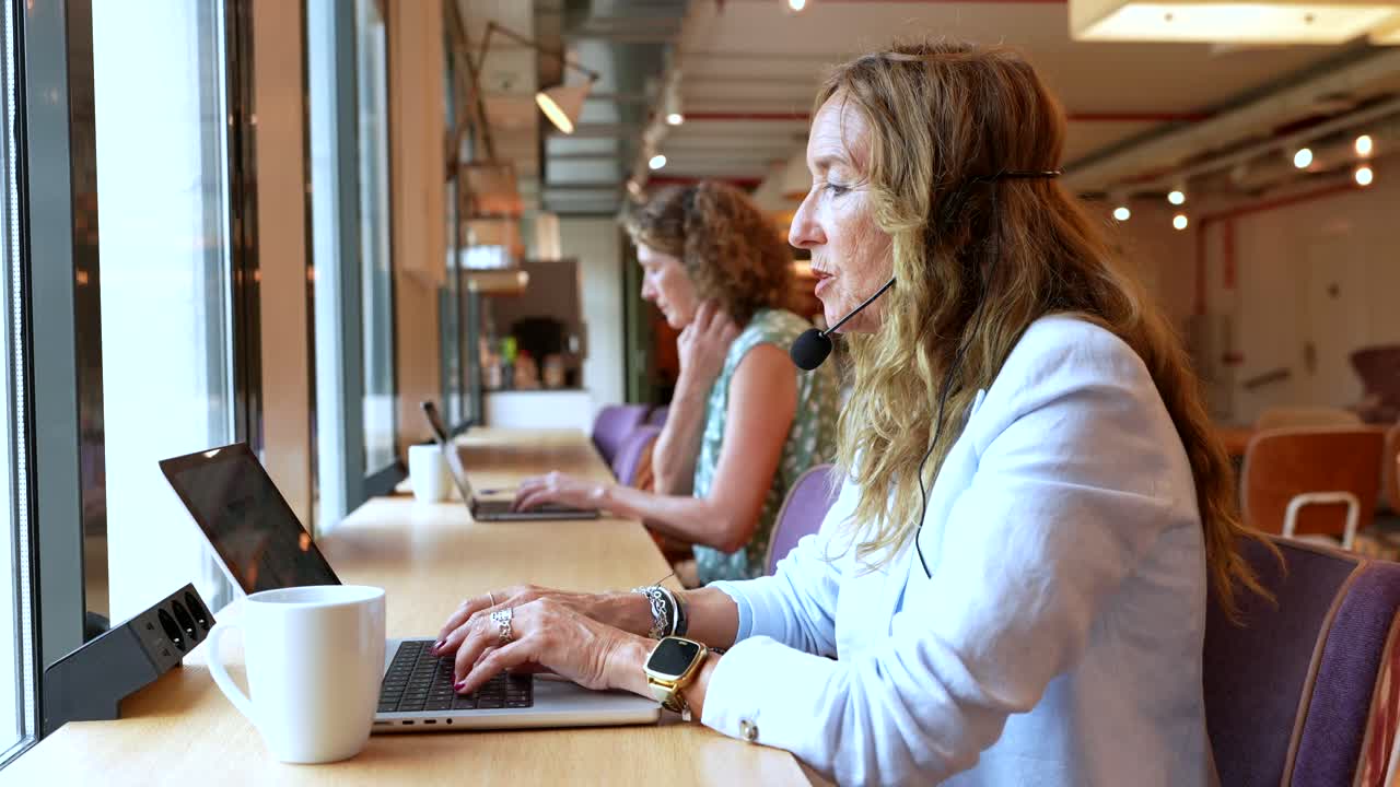 Women working in a modern office with laptops and headsets