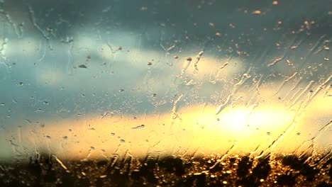 Agua-De-Lluvia-Golpeando-Un-Parabrisas-Mientras-Un-Auto-Conduce-Al-Atardecer