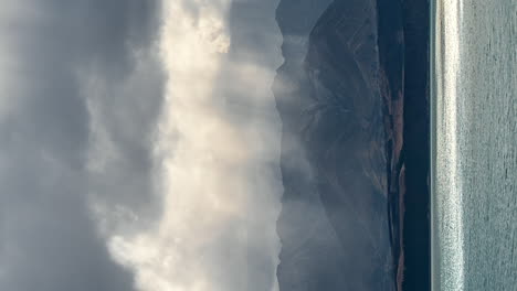 los rayos del sol brillando a través de las nubes sobre el lago pukaki, nueva zelanda - lapso de tiempo vertical
