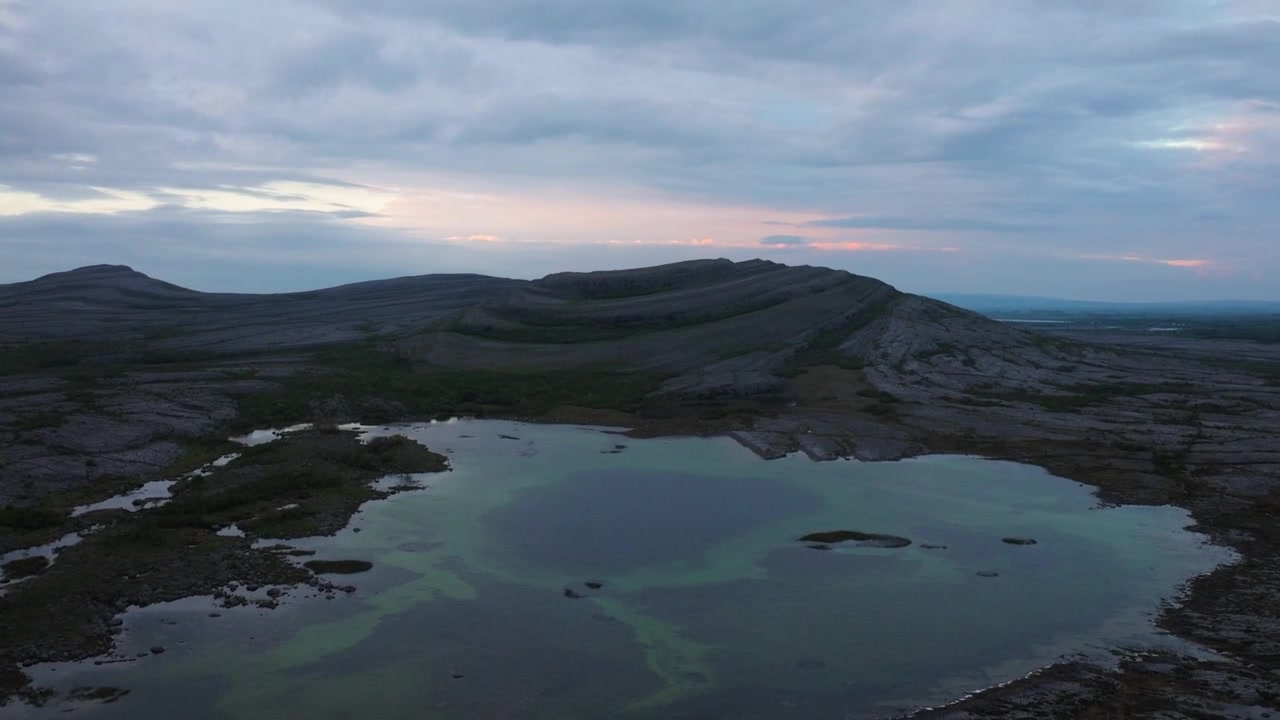 Mykt daggrylys bader de reflekterende dammene og kalksteinsryggene i The Burren. Ideelt for naturdokumentarer eller reiseinnhold.