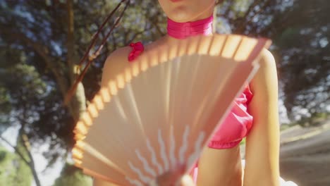 fashionable woman holding a fan outdoors