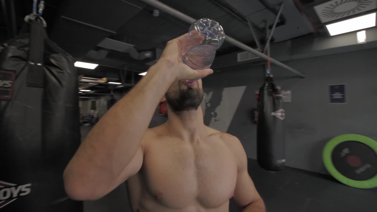 joven atlético haciendo ejercicio en el gimnasio descansando y bebiendo agua