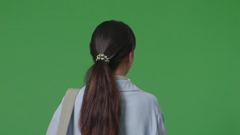 close up of back view asian teen girl student with a backpack walking in the green screen background studio