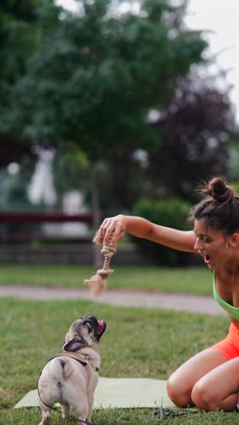 woman playing with her pug in the park