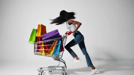 a joyful black woman pushes a shopping cart full of colorful bags
