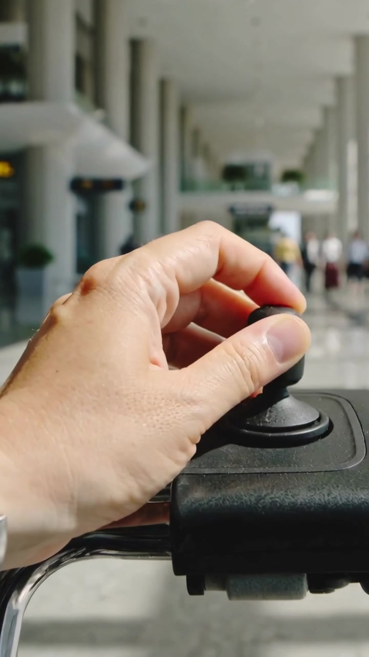 Vertical video: Settling fingers, adult turning black knob on metal rail in airport, locking handle